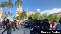 La policía conduce cerca de personas durante las protestas en contra y en apoyo al gobierno, en La Habana.