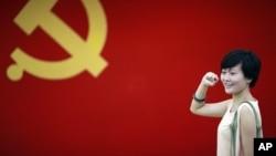 在上海的中共第一次代表大会会址，一名女子在中国共产党党旗下摆出宣誓姿势 （2012年7月1日）