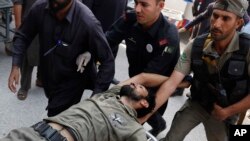 Pakistani security officials rush their colleague to a Peshawar hospital after the Taliban's brazen assault on a military base, Sept. 18, 2015.