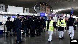 Des employés d'Air France passent devant la police anti-émeute CRS française à travers un terminal de l'aéroport Charles de Gaulle à Roissy le 22 février 2018.
