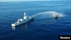 An aerial view shows a Japan Coast Guard patrol vessel spraying water at a fishing boat from North Korea, in an area called the Yamato Shallows in this handout photo taken in September 2017.