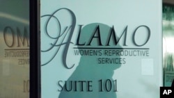 Senka radnika obezbeđenja na ulaznim vratima u Alamo servis za žensku reprodukciju, 7. oktobra 2021. u San Antoniju, u Teksas. (Foto: AP/Eric Gay)