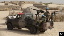 FILE - UN peacekeepers from Burkina Faso stand guard during a patrol through a neighborhood on the outskirts of Timbuktu, Mali. Hundreds of Malians are gathering in the northern desert town of Timbuktu, from Monday, March 31, 2014,