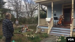 Musician Jodi Beder plays her cello as neighbors enjoy the music on March 20, 2020, in Mount Rainier, Maryland. Beder plans to hold daily cello concerts from her front porch as the new coronavirus has led to "social distancing measures." 
