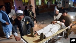 FILE - A wounded man is brought by stretcher into a hospital in Jalalabad city, capital of Nangarhar province, east of Kabul, June 16, 2018. 