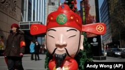 一名婦女正路過北京一處購物中心外面的財神爺雕像。（2011年2月28日）