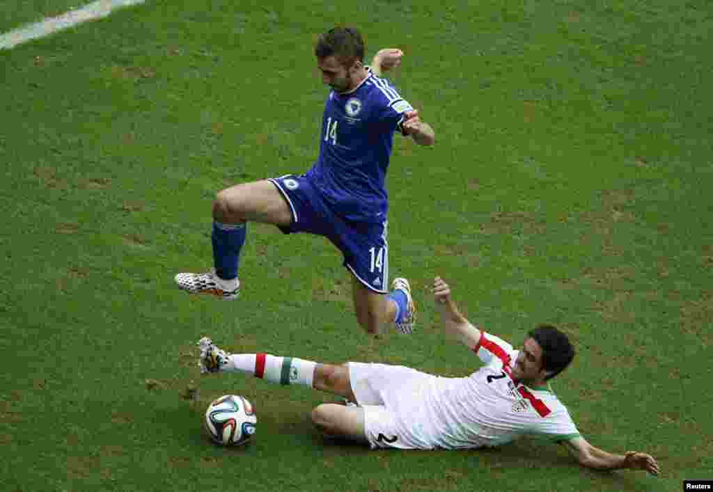 Bosnian Tino Sven Susic jumps over Iranian Khosro Heydari during their match at the Fonte Nova arena, in Salvador, June 25, 2014. 