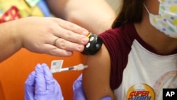 FILE - Parker McKenzie, 10, right, receives a Pfizer COVID-19 vaccine from a nurse practitioner during a COVID-19 vaccine clinic at Nationwide Children's Hospital in Columbus, Ohio, Nov. 3, 2021. 