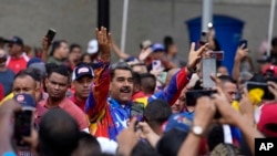 ARCHIVO - El presidente de Venezuela, Nicolás Maduro, saluda a jóvenes partidarios en una marcha contra sanciones estadounidenses en Caracas, Venezuela, el 17 de mayo de 2024.