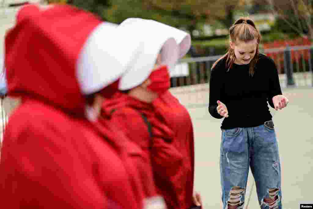 Una joven a favor de la nominación de Amy Coney Barrett a la Corte Suprema de EE. UU. ora frente a manifestantes opuestos a la nominación, el lunes 26 de octubre de 2020.
