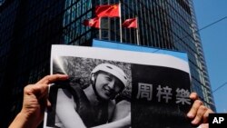 A protester holds a photo of Chow Tsz-Lok during a memorial flash mob to remember him, Nov. 8, 2019. Chow, a Hong Kong university student, fell off a parking garage after police fired tear gas during clashes with protesters and died Friday.