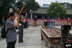 兩個女孩在北京東岳廟裡燒香。 （2024年8月7日）