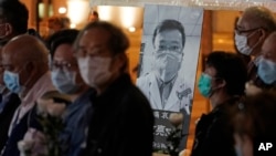People wearing masks, attend a vigil for Chinese doctor Li Wenliang, in Hong Kong, Friday, Feb. 7, 2020. The death of a young doctor who was reprimanded for warning about China's new virus triggered an outpouring Friday of praise for him and fury…