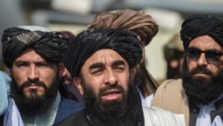 Taliban spokesman Zabihullah Mujahid, center, addresses a media conference at the airport in Kabul on Aug. 31, 2021.