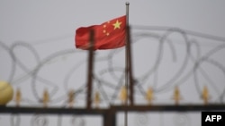 资料照片：在新疆喀什市以南的一个居住区，一面中国国旗在铁丝网后面飘扬。(2019年6月4日)