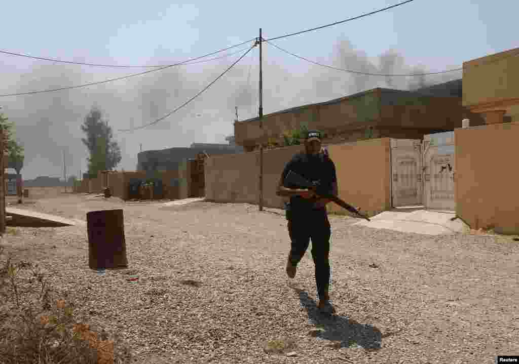 "Asaib Ahlul Haq" shia guruhi jangchisi otishmadan o'zini panaga olmoqda, 1-sentabr, 2014-yil.